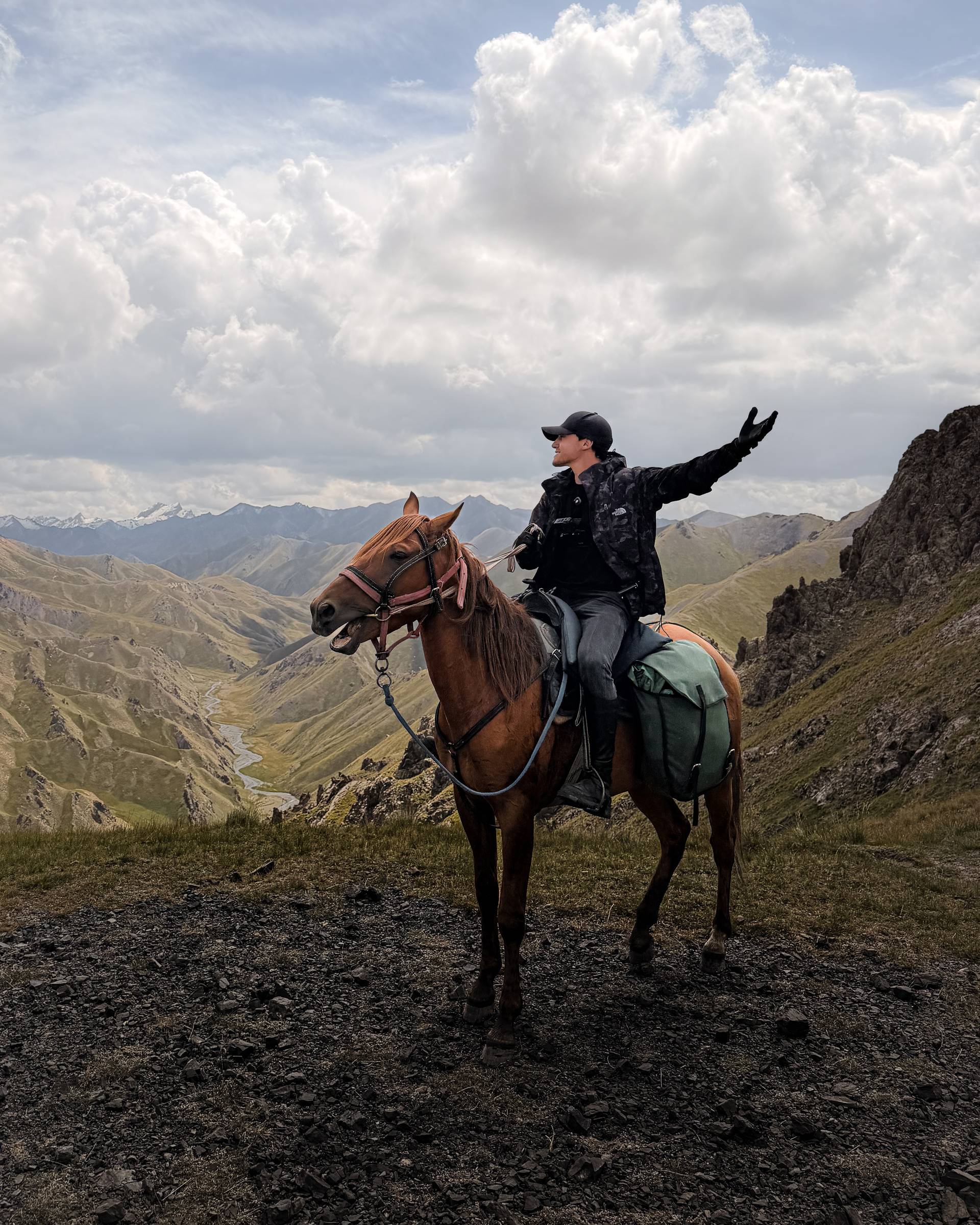Rider on horseback celebrating at a mountain pass, Kyrgyzstan horse trek