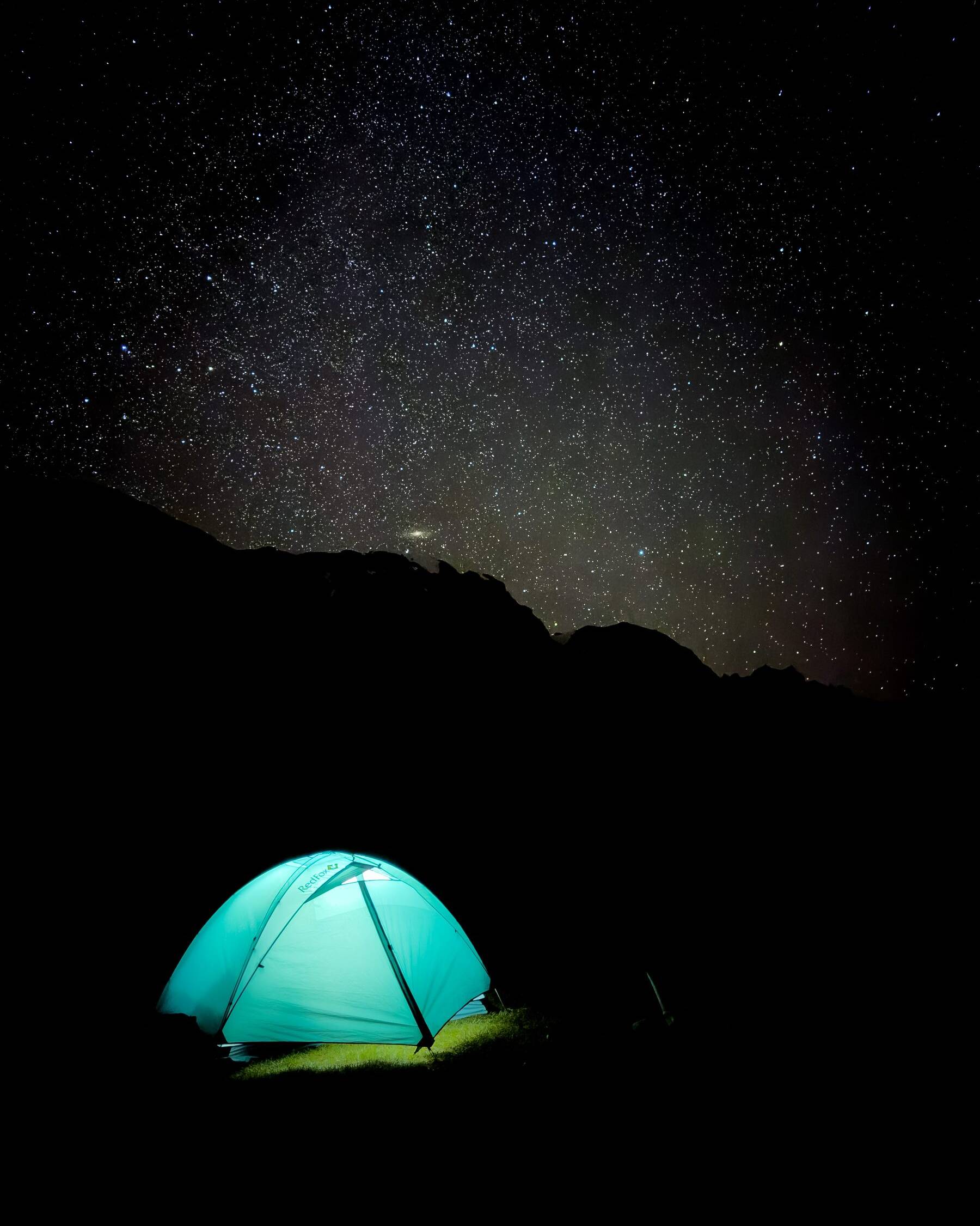 Glowing tent under a starry night sky in the mountains, Kyrgyzstan