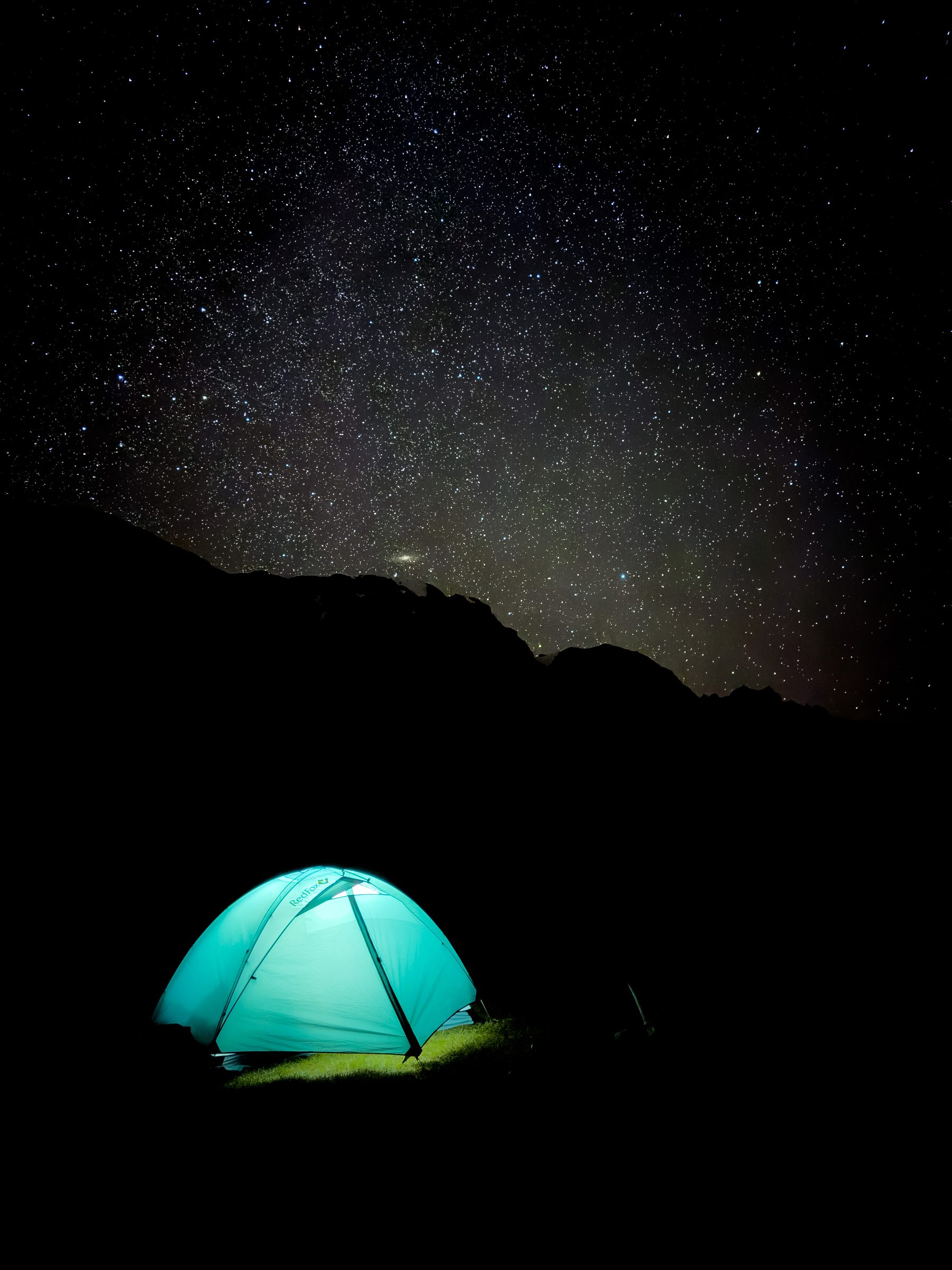 Glowing tent under a starry night sky in the mountains, Kyrgyzstan