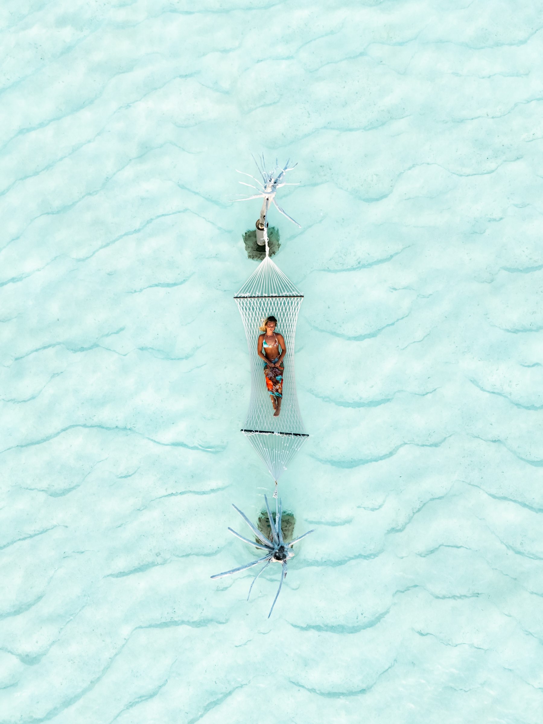 Aerial view of a hammock over clear lagoon water, Maldives