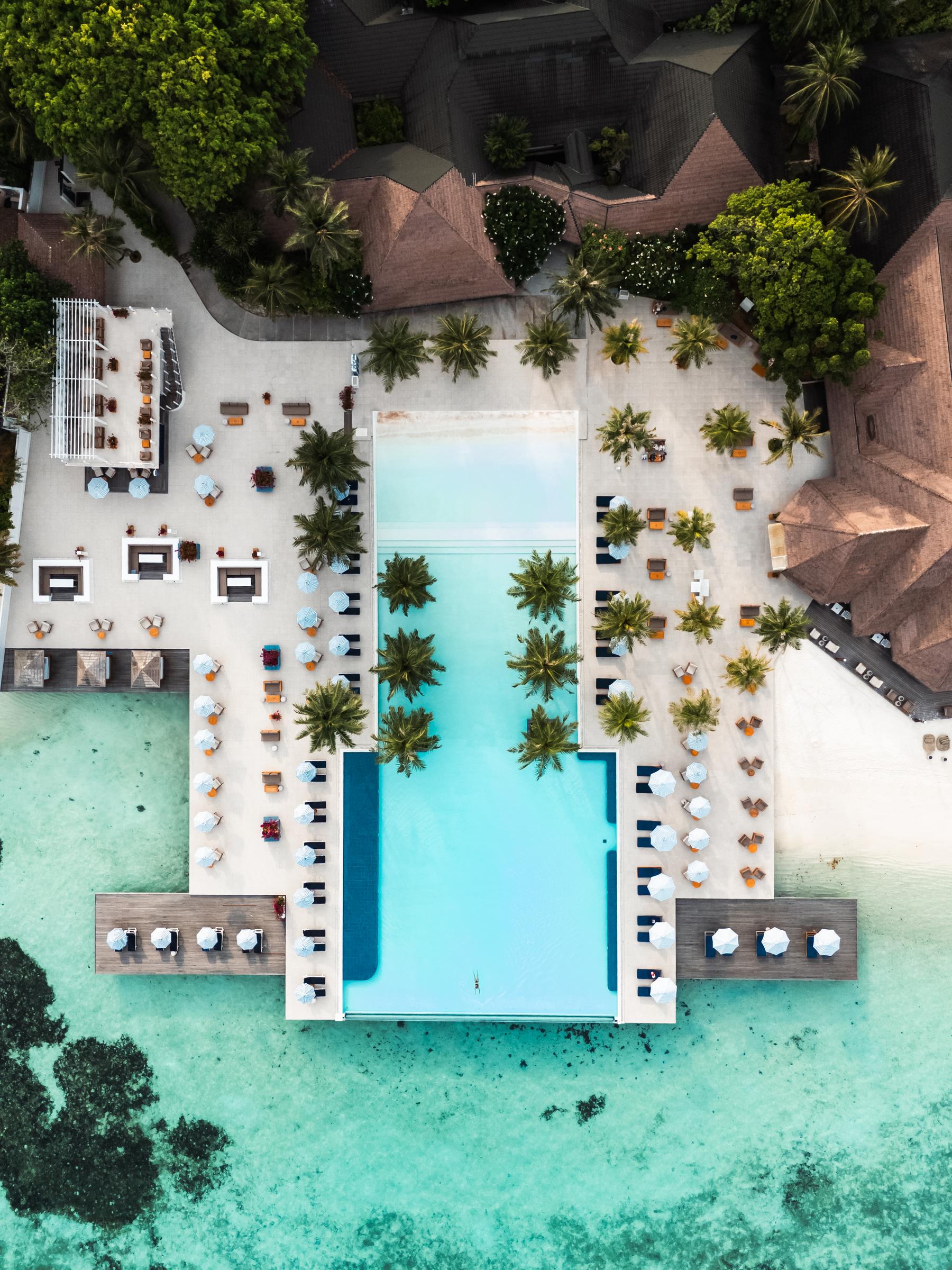 Aerial view of a resort pool and restaurant over turquoise water, Maldives