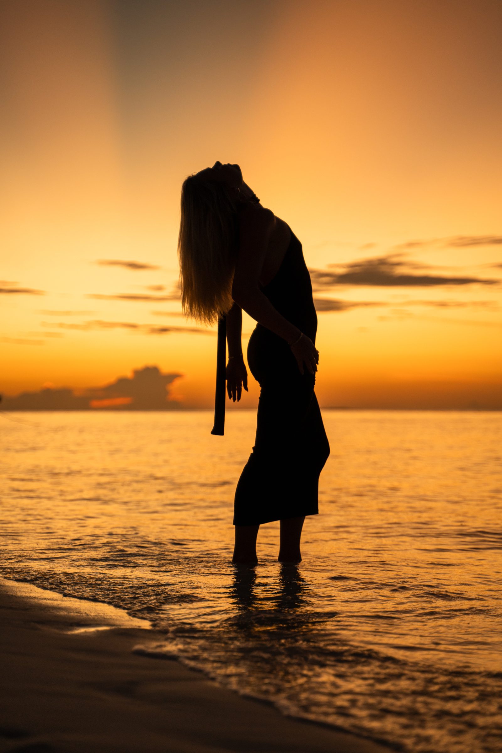 Silhouette of a woman in the shallows at sunset, Maldives