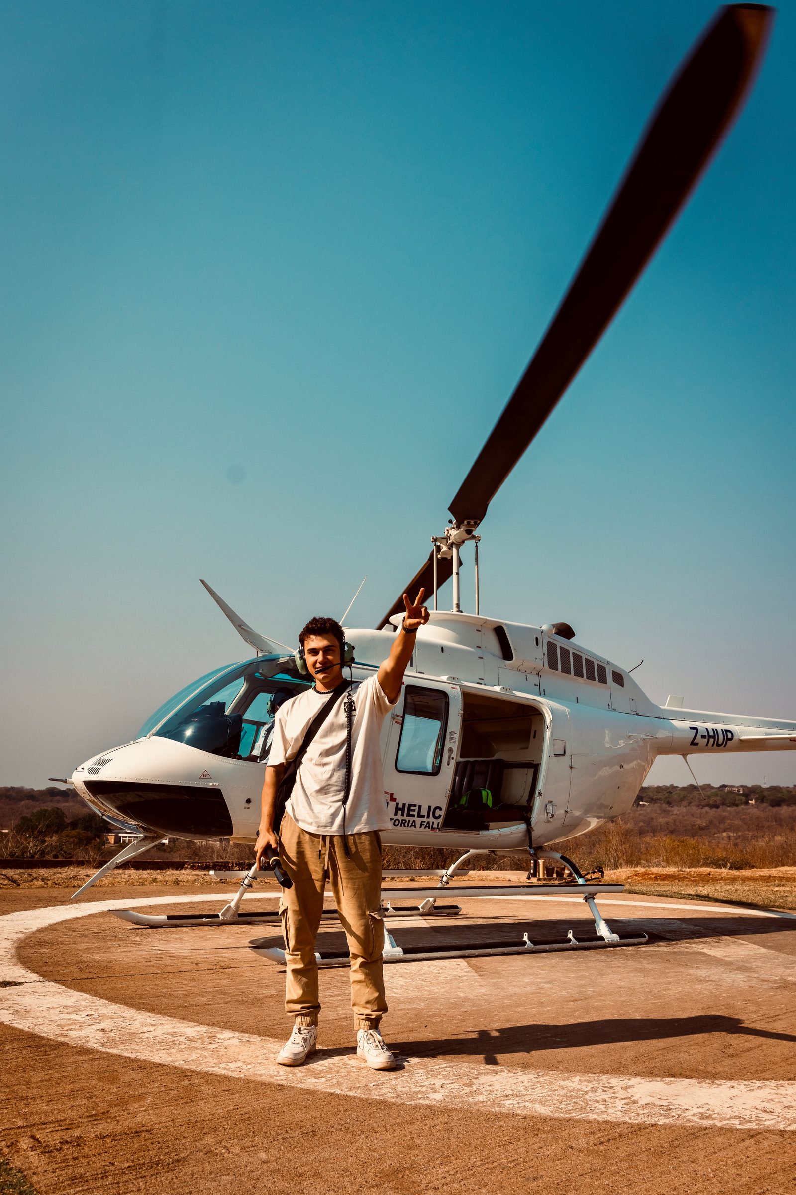 Photographer standing by a safari helicopter on a landing pad
