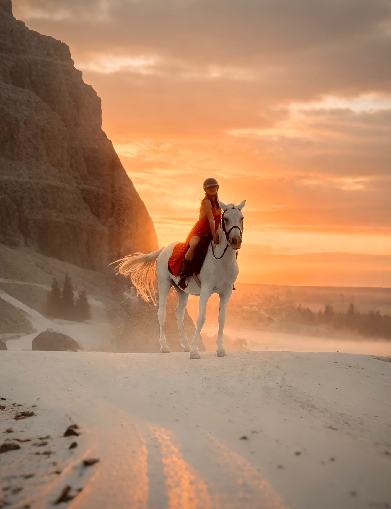 Rider on a white horse in a desert canyon at sunset