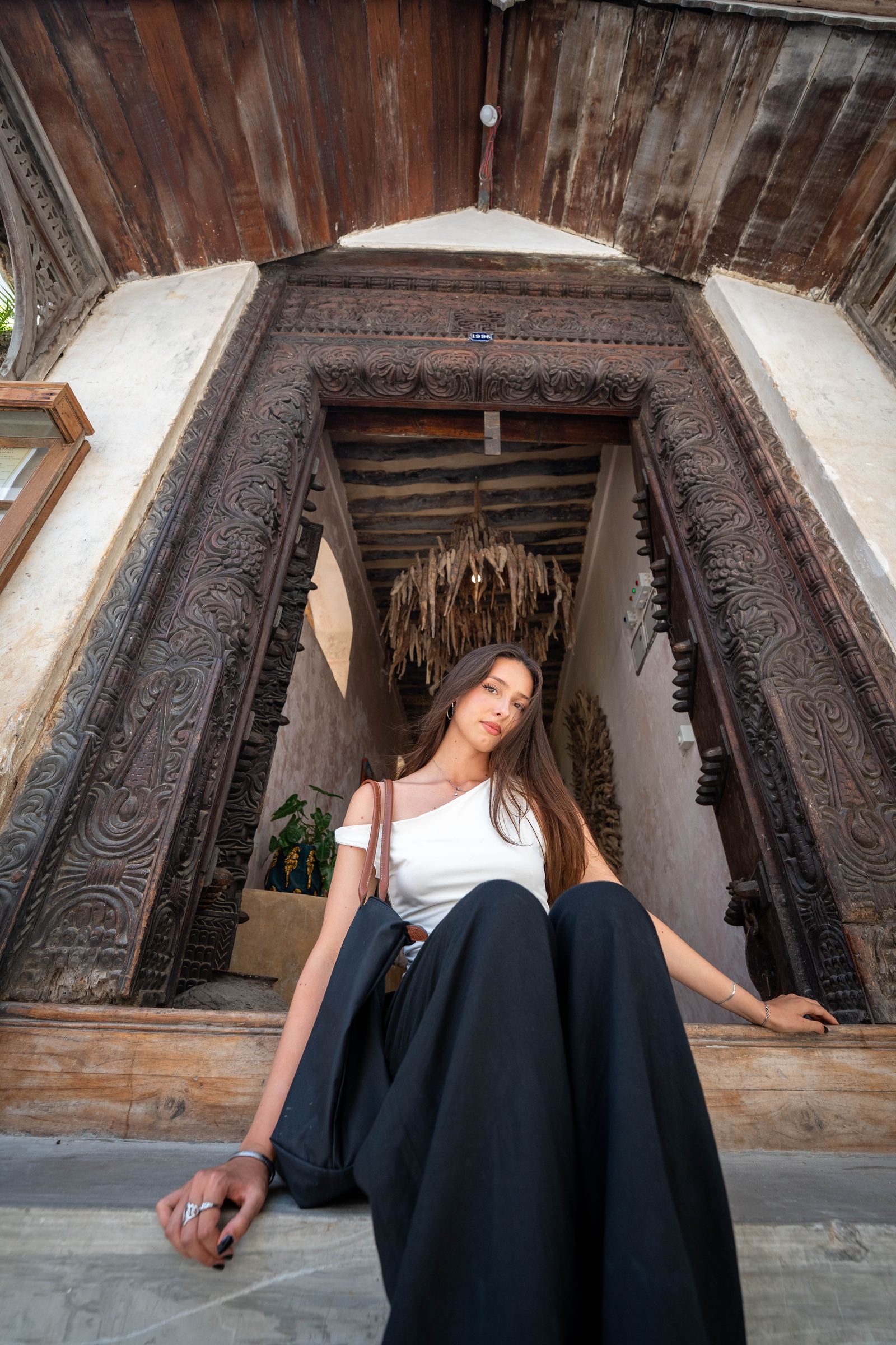 Woman sitting in a carved Swahili doorway, Zanzibar