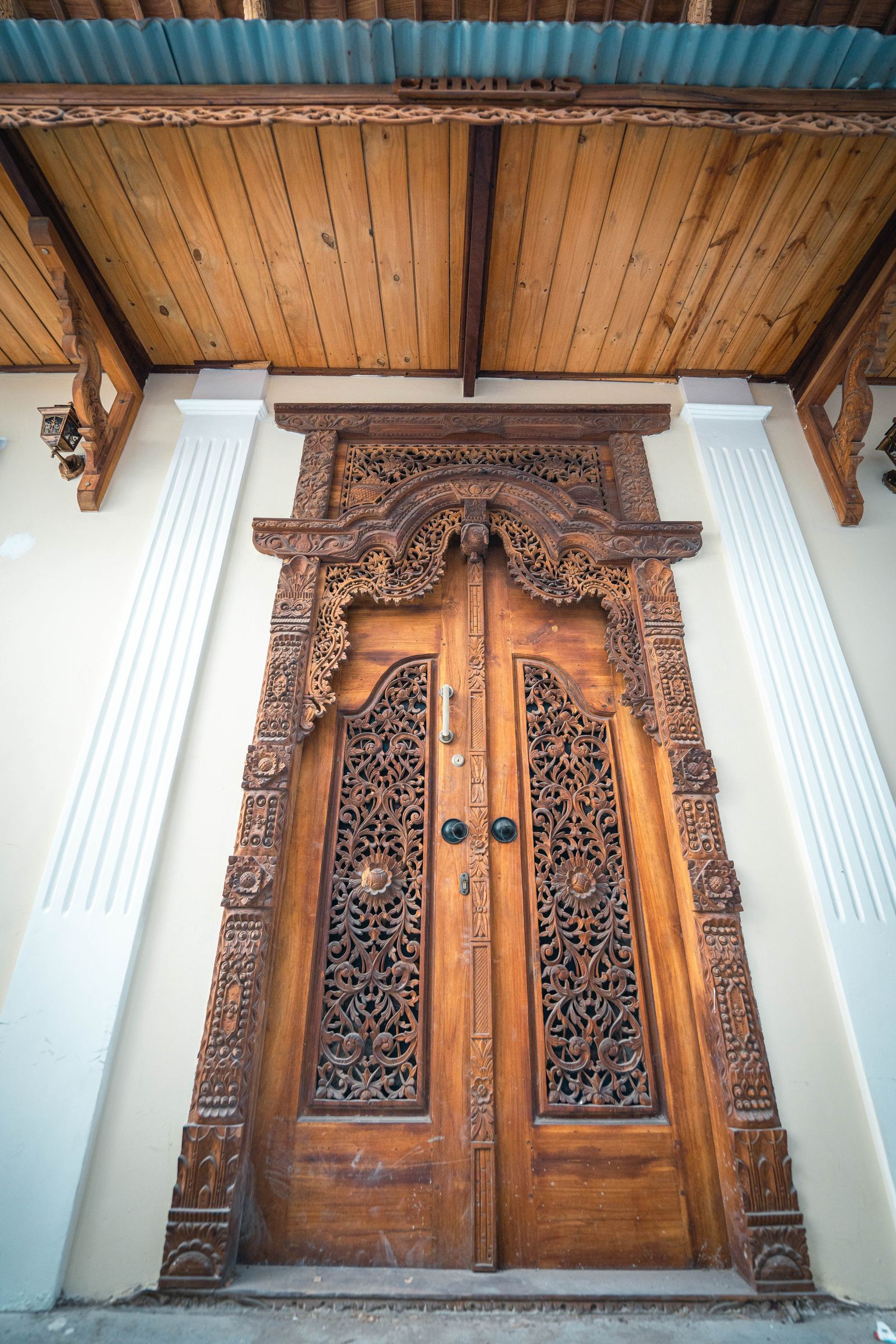Ornate carved wooden Zanzibar door under a timber veranda