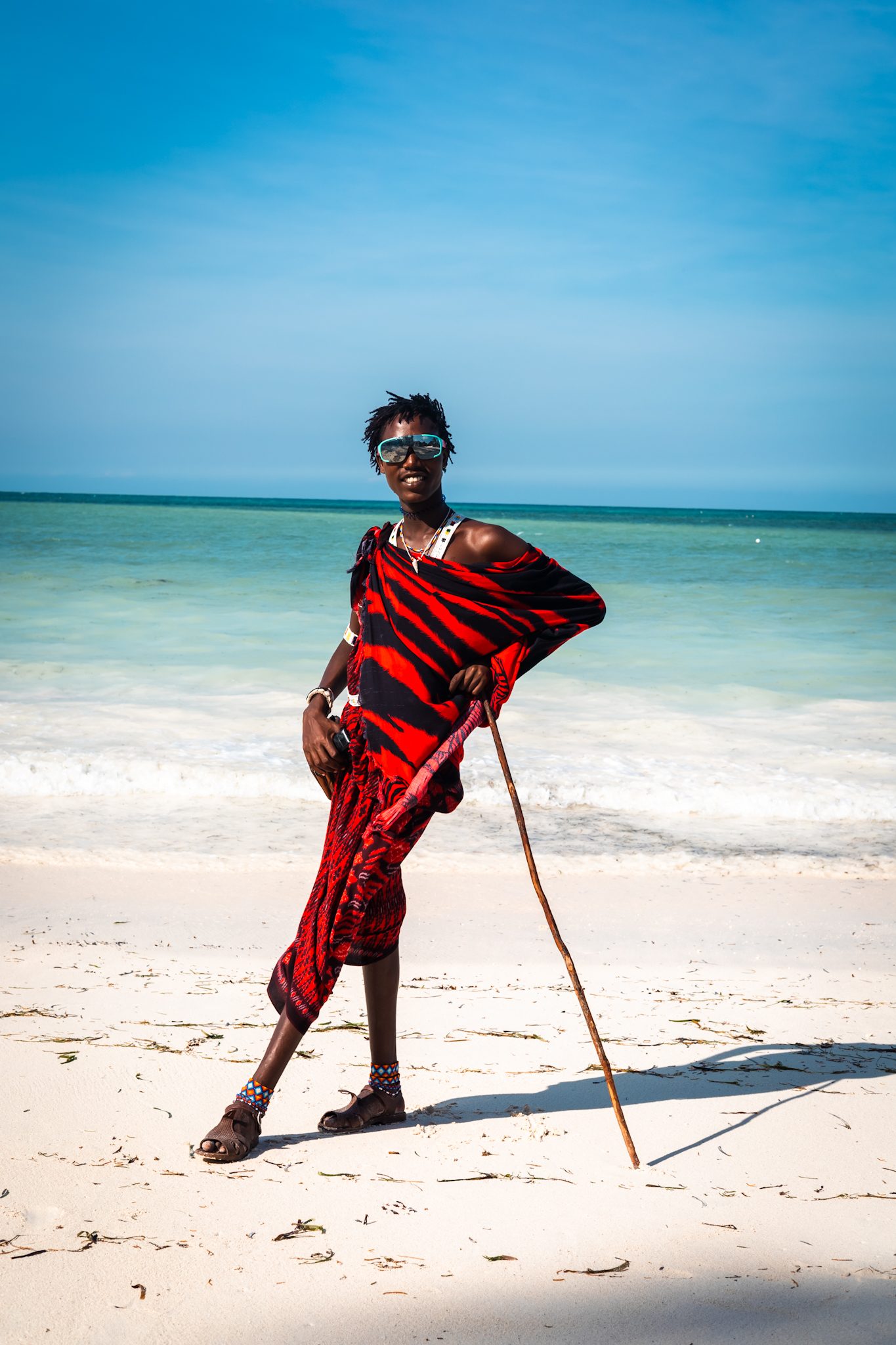 Maasai man in traditional red shuka posing on a Zanzibar beach